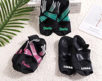 May include: Three pairs of black yoga socks with colorful stripes. The socks have the names "Doris", "Paula", and "Linda" written on them.