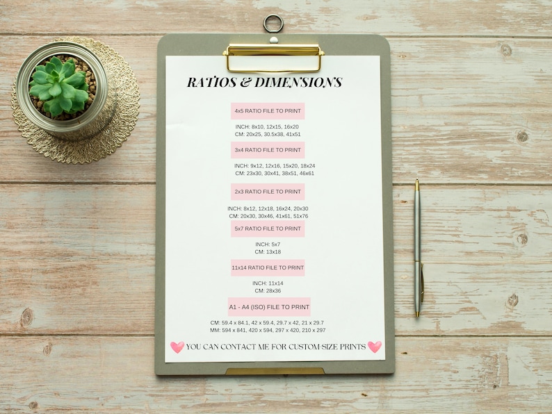 May include: A white clipboard with a gray background and gold binder clip. The clipboard has a list of different paper sizes and their corresponding dimensions in inches and centimeters. The text on the clipboard reads "Ratios & Dimensions".