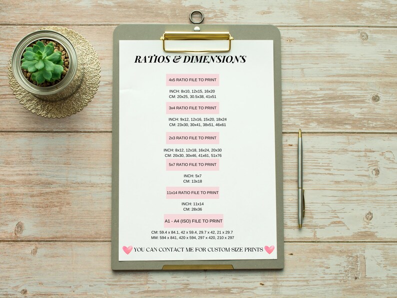 May include: A white clipboard with a gray background and gold binder clip. The clipboard has a list of different paper sizes and their corresponding dimensions in inches and centimeters. The text on the clipboard reads "Ratios & Dimensions".