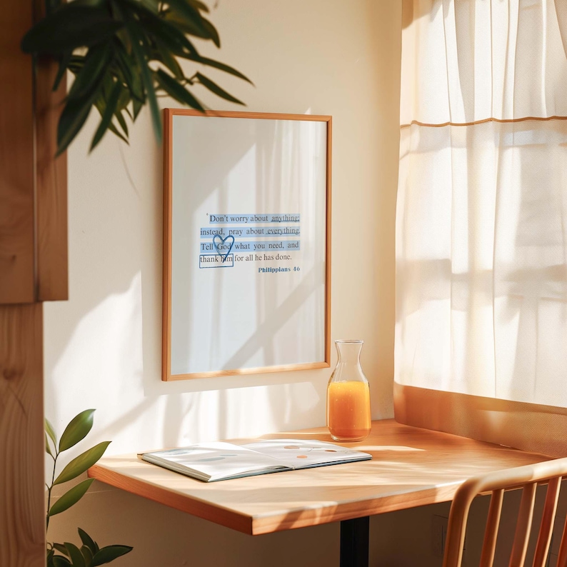 May include: A framed inspirational quote on a white wall with a wooden desk and a glass pitcher of orange juice. The quote reads: "Don't worry about anything instead, pray about everything Tell God what you need, and thank God for all he has done. Philippians 4:6"