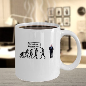 Puede incluir: Taza de café de cerámica blanca llena de líquido oscuro. La taza presenta un gráfico de evolución en blanco y negro con el texto "Go back, we screwed up!" y una persona con traje.