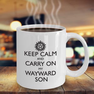 Puede incluir: Taza de café de cerámica blanca con un diseño en blanco y negro. La taza presenta un símbolo con una estrella y un círculo, y el texto "Keep Calm and Carry On My Wayward Son".