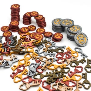 Op de afbeelding: Een verzameling spelonderdelen, waaronder stapels rode en grijze munten met gele accenten, en een verscheidenheid aan sleutels in goud-, zilver- en bronskleuren. De stukken zijn verspreid op een witte ondergrond.