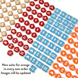 May include: A collection of small, shaped game tokens in beige, red, blue, and orange. The tokens feature white icons of lightning bolts, leaves, and houses. Some tokens are marked with a white x2 symbol. Text reads: New color for orange in every new order. Images will be updated.