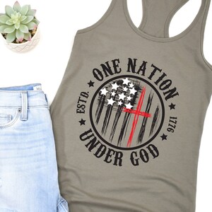 May include: A green tank top with a black and red circle graphic that says "One Nation Under God" with a stylized American flag and the text "Estd. 1776".
