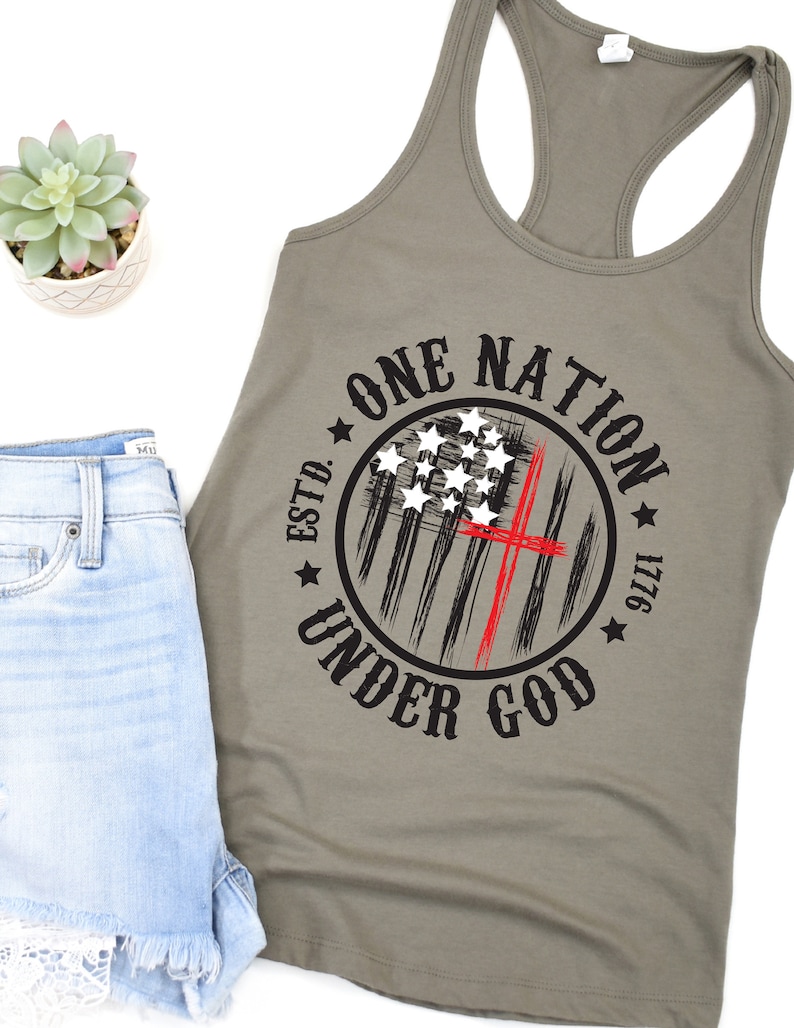 May include: A green tank top with a black and red circle graphic that says "One Nation Under God" with a stylized American flag and the text "Estd. 1776".