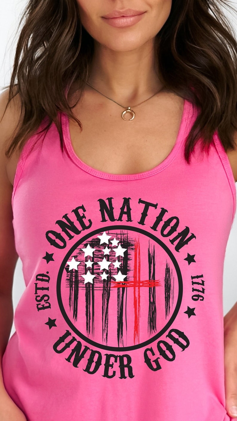 May include: Pink tank top with a black and white graphic of an American flag with a red cross in the center. The graphic is in a circle with the text "One Nation Under God" and "Estd. 1776" around the circle.