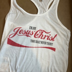 May include: White tank top with a red Coca-Cola-inspired graphic that says "Enjoy Jesus Christ Thou Shalt Never Thirst".