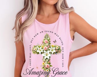 May include: Pink sleeveless tank top with a floral cross design and the text "I once was lost, but now am found. Was blind, but now I see. Amazing Grace".