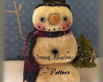 May include: A snowman stack with a black top hat, red and black scarf, and a green leafy branch. The snowman is made of white fabric and has a brown nose and black eyes. The text "Snowman Stack" is written above the snowman and "Sweet Meadows Farm E-Pattern" is written below the snowman.