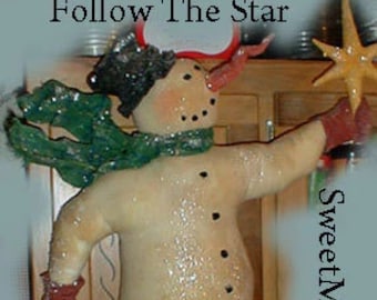 May include: A handmade snowman figurine with a green scarf, red mittens, and a black hat, holding a golden star. The text "Follow The Star" is above the snowman. The snowman is decorated with glitter.