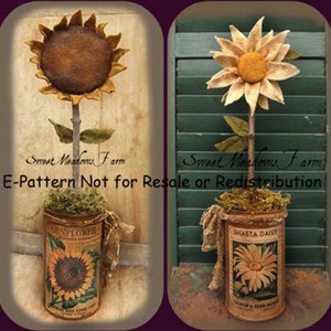 Op de afbeelding: Twee felt-zonnebloemarrangementen in vintage blikken. De zonnebloemen zijn gemaakt van bruin felt met gele centra. De blikken zijn gelabeld "Sunflower" en "Shasta Daisy". De tekst "Sweet Meadows Farm E-Pattern Not for Resale or Redistribution" is zichtbaar onderaan de afbeelding.