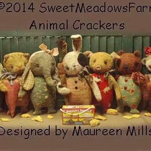 May include: A group of handcrafted plush animal toys, including a bear, cat, elephant, rabbit, and monkey, each with distinct clothing and features. The image also shows a box of animal crackers and text that reads "Animal Crackers" and "Designed by Maureen Mills."