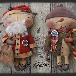 Puede incluir: Dos muñecas de trapo hechas a mano, una vestida de Papá Noel con un saco de juguetes y la otra de muñeco de nieve con un bastón de caramelo. Ambas muñecas tienen un estilo rústico y vintage.