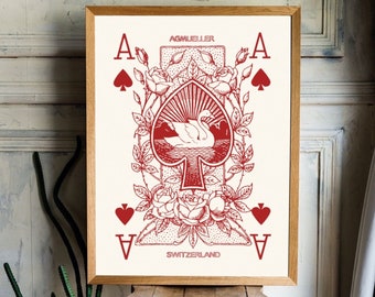 May include: A red and white illustration of the Ace of Spades playing card with two swans in the center. The card is surrounded by roses and leaves. The text "AGMUELLER" and "SWITZERLAND" are printed on the card.