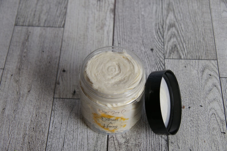 K&ouml;nnte beinhalten: Ein klares Glas mit einem wei&szlig;en Deckel, gef&uuml;llt mit einer wei&szlig;en Creme. Das Glas hat ein Etikett mit der Aufschrift "Wright Soap Co. Oatmeal & Honey".