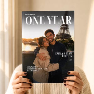 Può includere: Una copertina di un fotolibro personalizzato intitolata ONE YEAR 365 DAYS OF US che mostra una coppia che si abbraccia davanti alla Torre Eiffel al tramonto. Il testo recita EMMA & LIAM, EMMA & LIAM EDITION, HOW WE MET, WHAT I LOVE ABOUT YOU e 365 MEMORIES.
