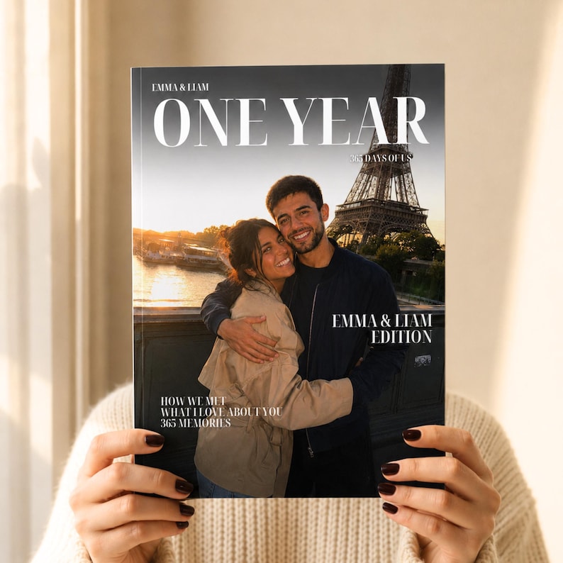 K&ouml;nnte beinhalten: Ein personalisiertes Fotobuch-Cover mit dem Titel ONE YEAR 365 DAYS OF US, das ein Paar zeigt, das sich vor dem Eiffelturm bei Sonnenuntergang umarmt. Der Text lautet EMMA & LIAM, EMMA & LIAM EDITION, HOW WE MET, WHAT I LOVE ABOUT YOU und 365 MEMORIES.