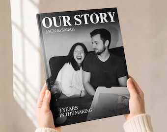 Könnte beinhalten: Ein schwarz-weißes Fotobuch-Cover mit einem lächelnden Paar und dem in Weiß gedruckten Text OUR STORY, JACK & SARAH sowie 3 YEARS IN THE MAKING. Das Cover zeigt ein spontanes Bild von zwei Personen, die mit einem Weinglas und Pizzakarton sitzen.