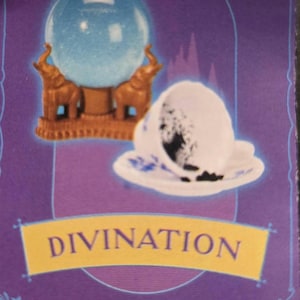 May include: A divination card featuring a blue crystal ball atop a brown stand with elephant figures, and a white teacup with a dark pattern. The word "DIVINATION" is displayed on a yellow banner against a purple background.