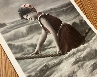 Cartolina d'epoca del 1900: donna su una corda tra le onde dell'oceano
