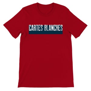 May include: Red short sleeve t-shirt featuring a navy blue horizontal banner with the text 'CARTES BLANCHES' in a distressed, white sans-serif font. The shirt is a classic crew neck style and appears to be made of a soft, comfortable fabric.