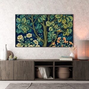 May include: A dark wood entertainment center with a tapestry print of a tree with flowers and birds hanging above it. The center has three shelves and two doors. A lamp with a beige shade is on the right side of the center.