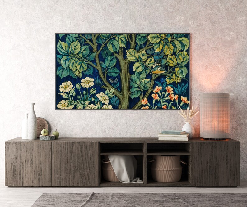 May include: A dark wood entertainment center with a tapestry print of a tree with flowers and birds hanging above it. The center has three shelves and two doors. A lamp with a beige shade is on the right side of the center.