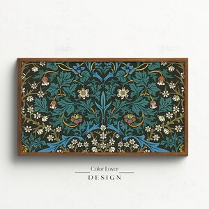 Puede incluir: Una impresi&oacute;n enmarcada de un patr&oacute;n floral vintage en tonos azules, verdes y blancos. El patr&oacute;n presenta flores y hojas estilizadas, creando un dise&ntilde;o sim&eacute;trico. El marco es de madera marr&oacute;n.