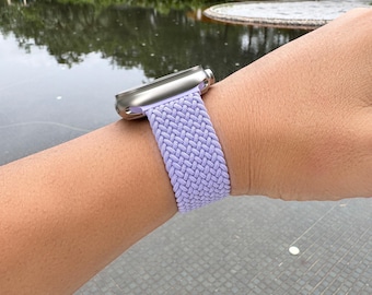 May include: A silver Apple Watch with a light purple braided band.