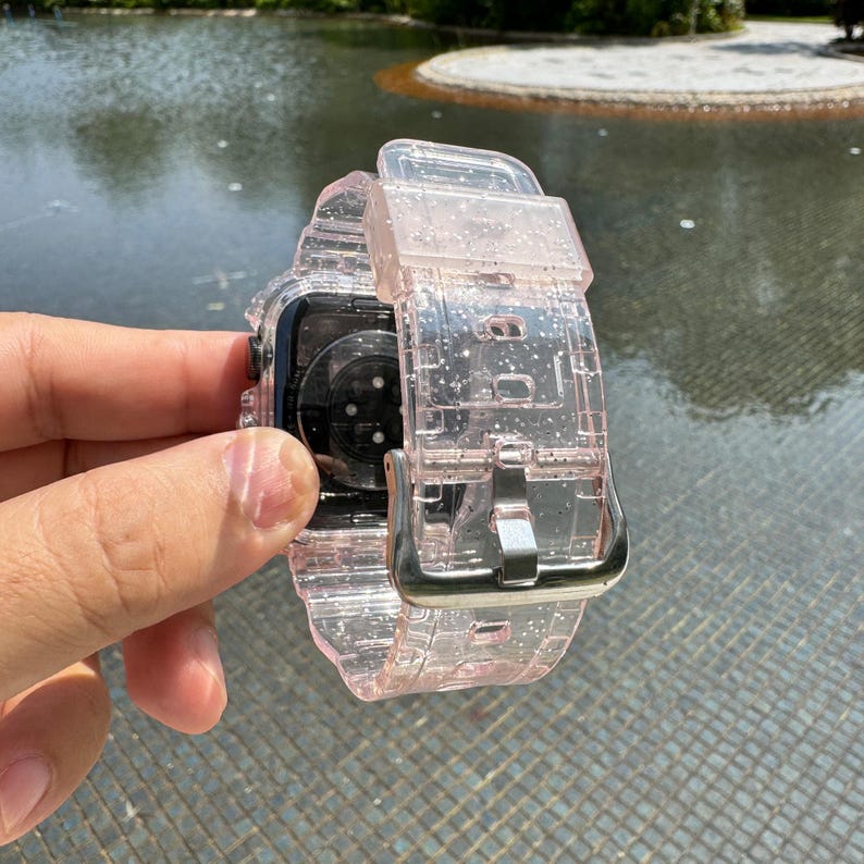 Pu&ograve; includere: Un cinturino per Apple Watch trasparente rosa glitterato con fibbia argentata.