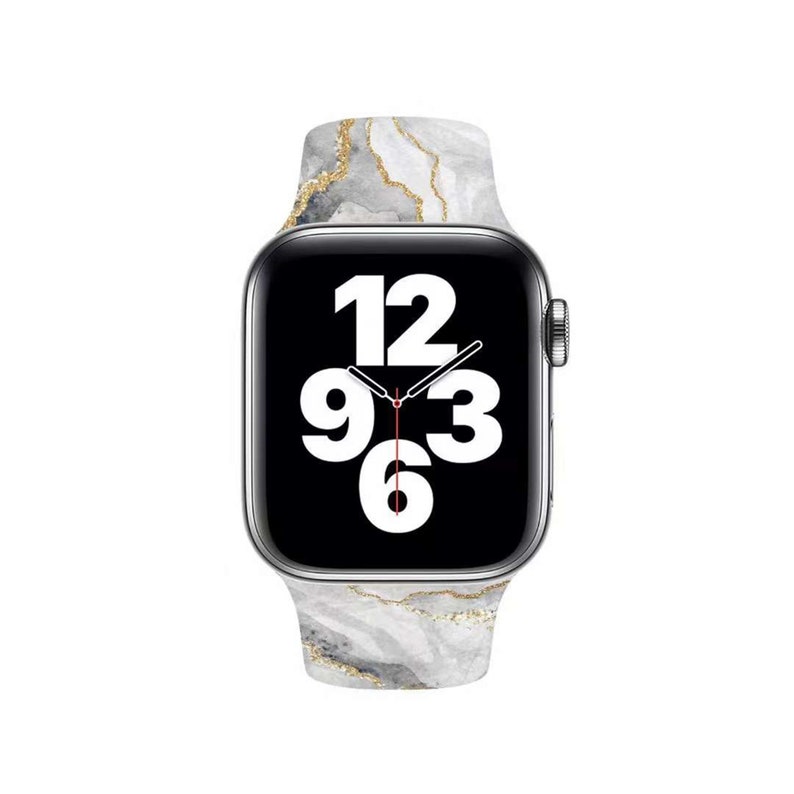 May include: A silver Apple Watch with a white and gold marble-patterned band. The watch face displays the time with black numbers on a black background.