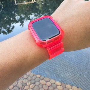 May include: A bright pink clear plastic watch band with a matching case for an Apple Watch.