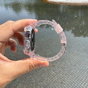 Pu&ograve; includere: Un cinturino per orologio rosa trasparente con una cassa trasparente per un Apple Watch. Il cinturino &egrave; realizzato in un materiale flessibile e gommoso.