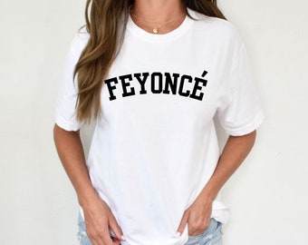 Può includere: Maglietta bianca con testo nero che recita "FEYONCÉ" in un font universitario.