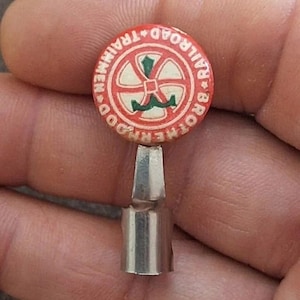 May include: A red and white metal pencil topper with the words "Other Road Railroad Trainmen" around a green and white wheel design.