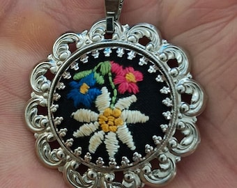 Colgante de filigrana plateada con flor bordada en cruz de los años 70