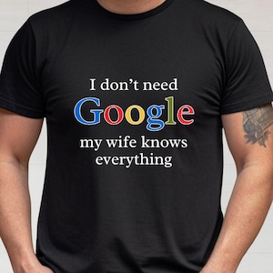 May include: A black t-shirt with the text "I don't need Google my wife knows everything" in colorful letters. The text is styled to look like the Google logo.
