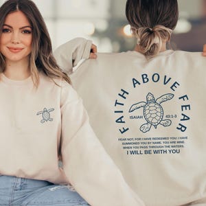 two women wearing matching white sweatshirts with a graphic design and text printed on the back.