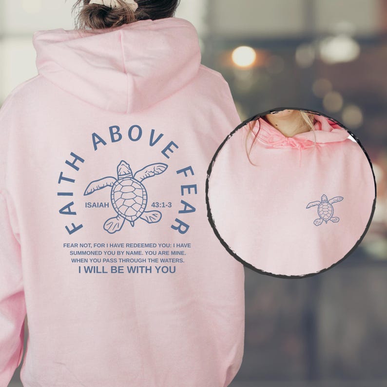 A person wearing a pink hoodie with a graphic design and text printed on it.