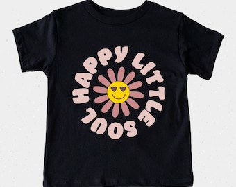 May include: Black t-shirt with a pink and yellow flower graphic. The flower has a smiley face with heart eyes and the text "Happy Little Soul" in a pink circle around it.