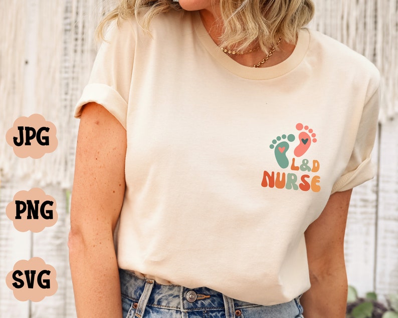 Puede incluir: Una camiseta blanca con un gr&aacute;fico colorido de dos huellas con corazones y el texto "L&D NURSE".
