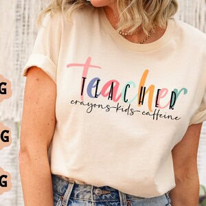 May include: A white t-shirt with the text "teacher crayons-kids-caffeine" in colourful lettering.