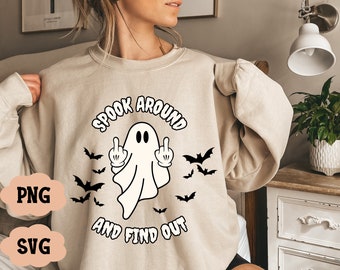 May include: Beige sweatshirt with a Halloween design. The graphic shows a cartoon ghost giving the middle finger, surrounded by bats, and the text "Spook Around and Find Out."