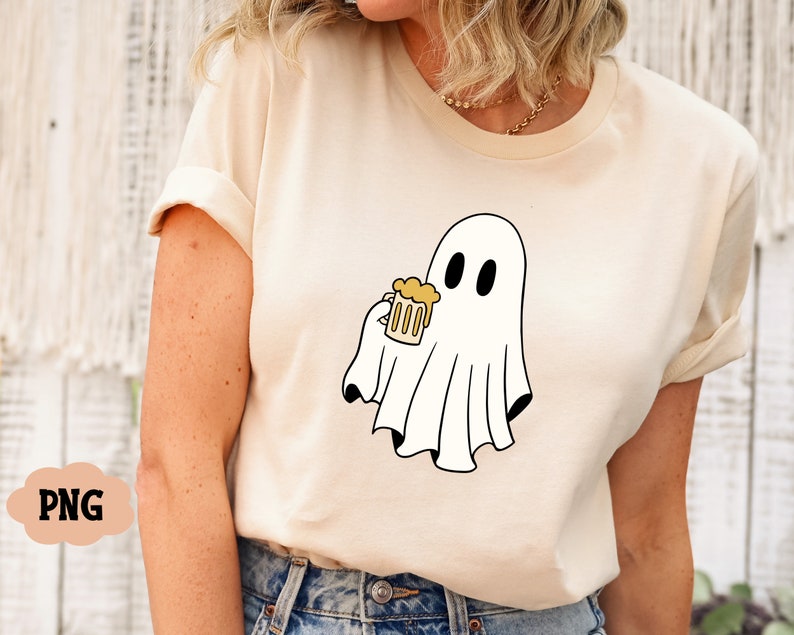 Pu&ograve; includere: Una maglietta bianca con un fantasma dei cartoni animati che tiene una boccale di birra gialla. Il fantasma ha due occhi neri e un corpo bianco a forma di lenzuolo.