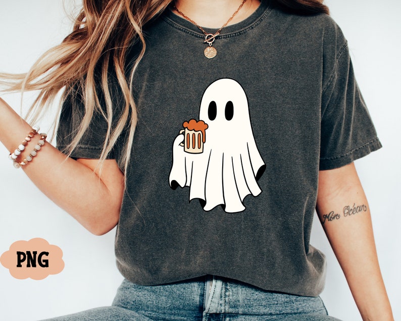 Pu&ograve; includere: Una maglietta grigia con un fantasma bianco che tiene un bicchiere di liquido arancione. Il fantasma ha due occhi neri e una piccola bocca. Il testo "More Beer" &egrave; scritto sulla manica destra della maglietta.
