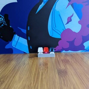 May include: Three mechanical keyboard keycaps in a row. The keycaps are white, red, and black.