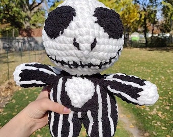 May include: White crocheted plush toy with black stripes and a black stitched face resembling Jack Skellington from the Nightmare Before Christmas.