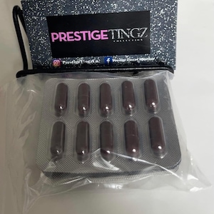 Peut inclure: Un blister contenant dix gélules marron foncé dans un sachet en plastique transparent, placé devant une carte de présentation mouchetée noire et blanche avec le texte PRESTIGETINGZ COLLECTION et des icônes de réseaux sociaux.
