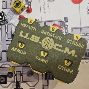 May include: A board game scene featuring a green game piece marked "U.S.O.C.M." alongside dice and miniature figures. The game board, with a map design, is partially visible, creating a strategic game setting.